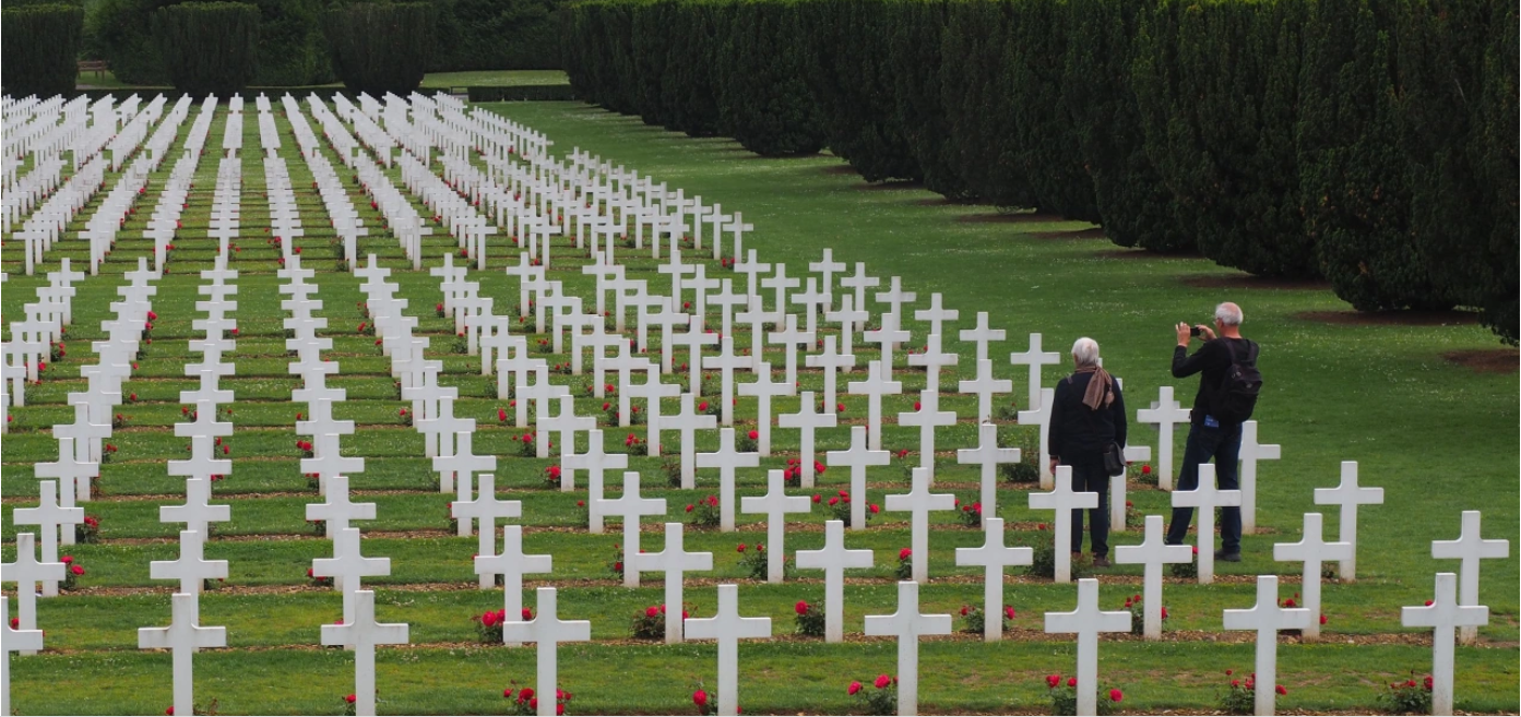 Rows of white crosses at a cemetery with two visitors