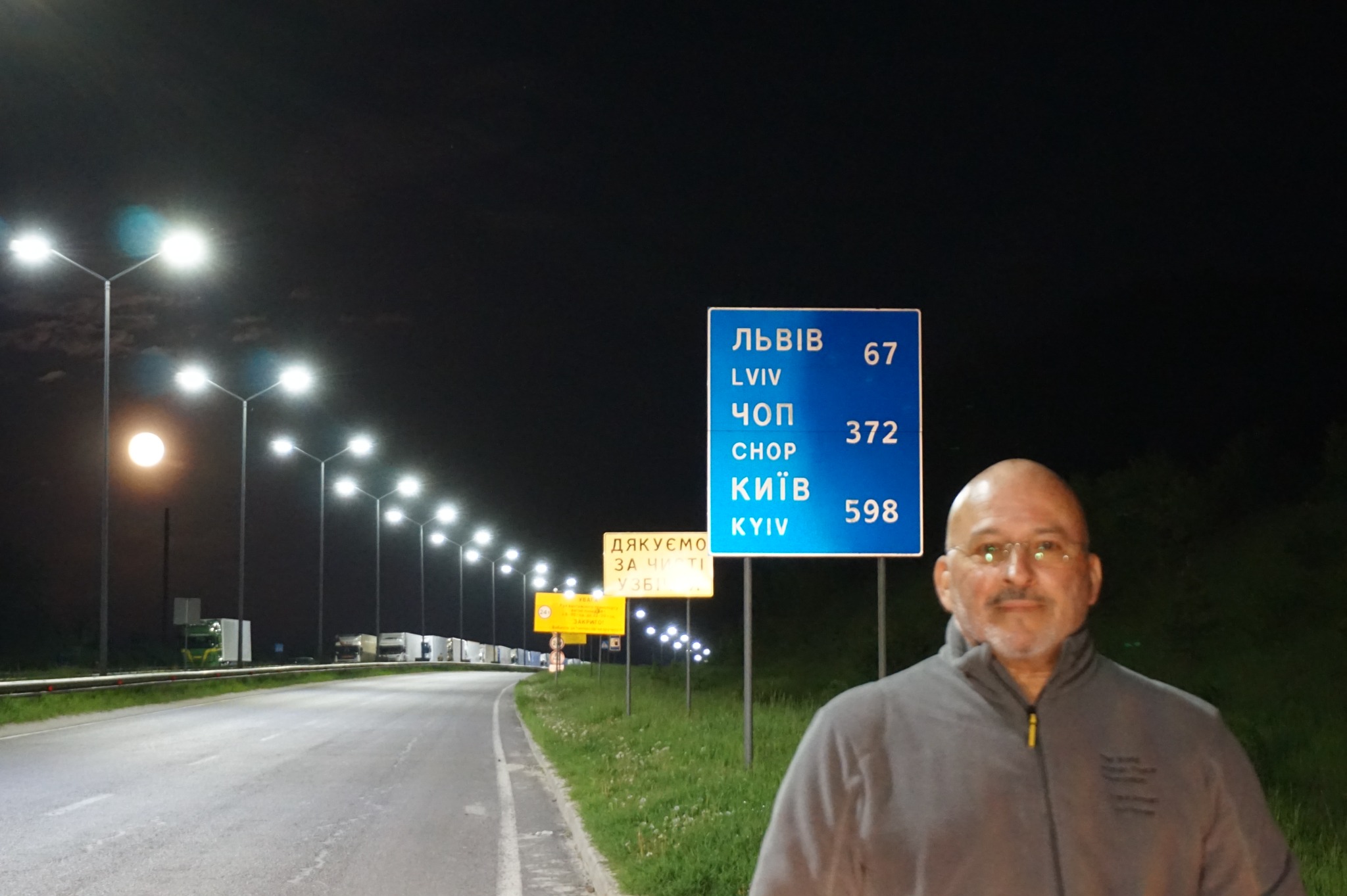 Francisco Armani beside a roadside sign listing Lviv, Chop and Kyiv during the Foundation's journey through Ukraine