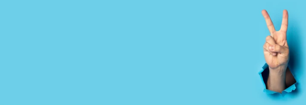 A hand making the peace sign against a sky-blue background